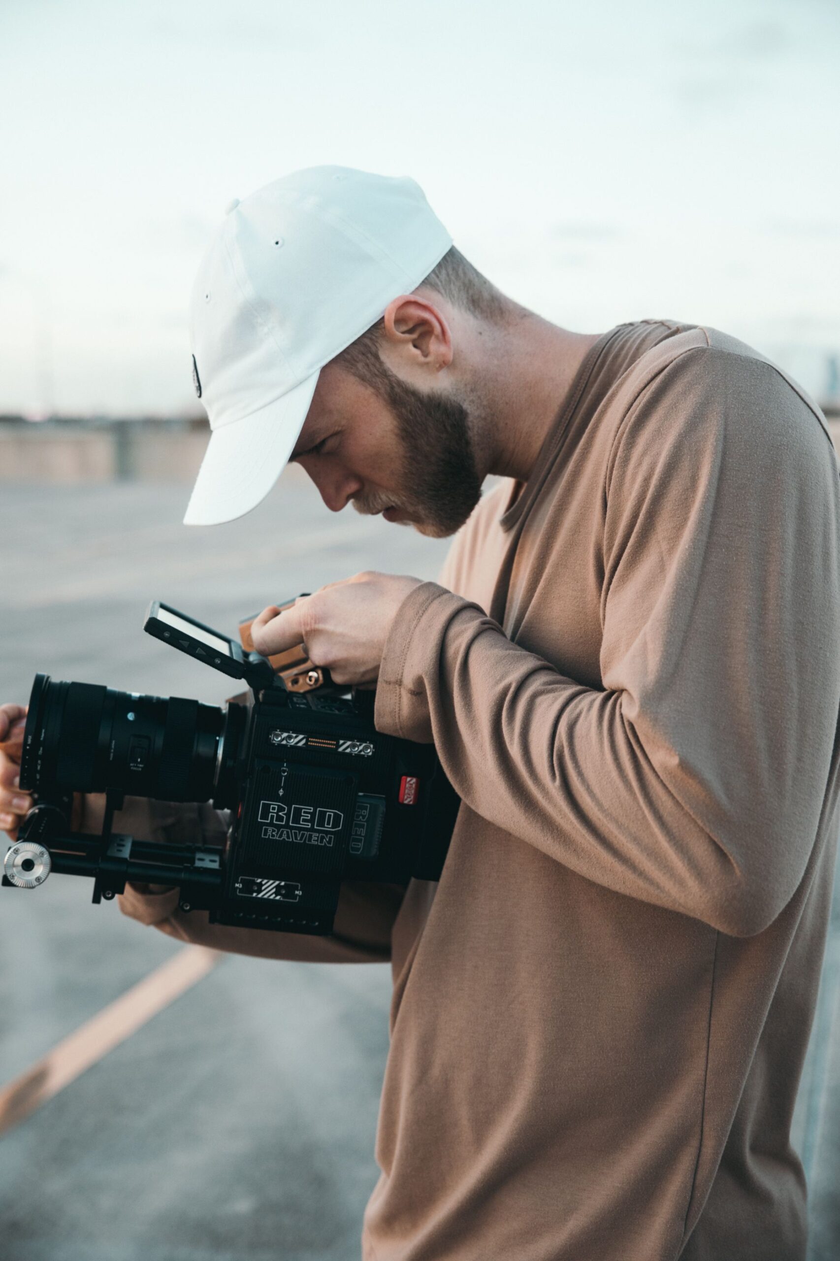 Man operating professional video camera in an outdoor urban setting, focused on filmmaking.