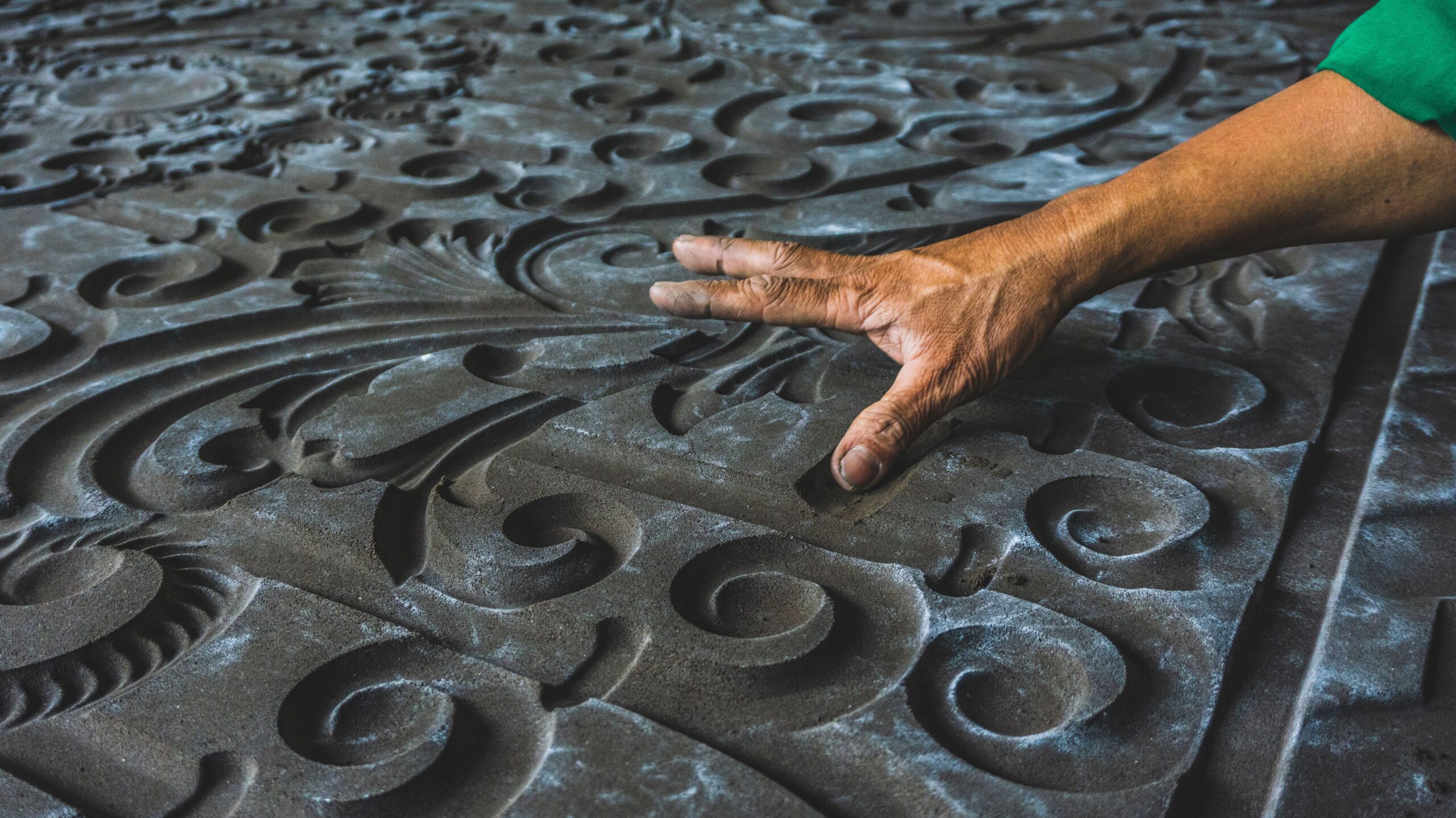 Close-up of a hand touching a detailed and ornate carved pattern, showcasing craftsmanship.