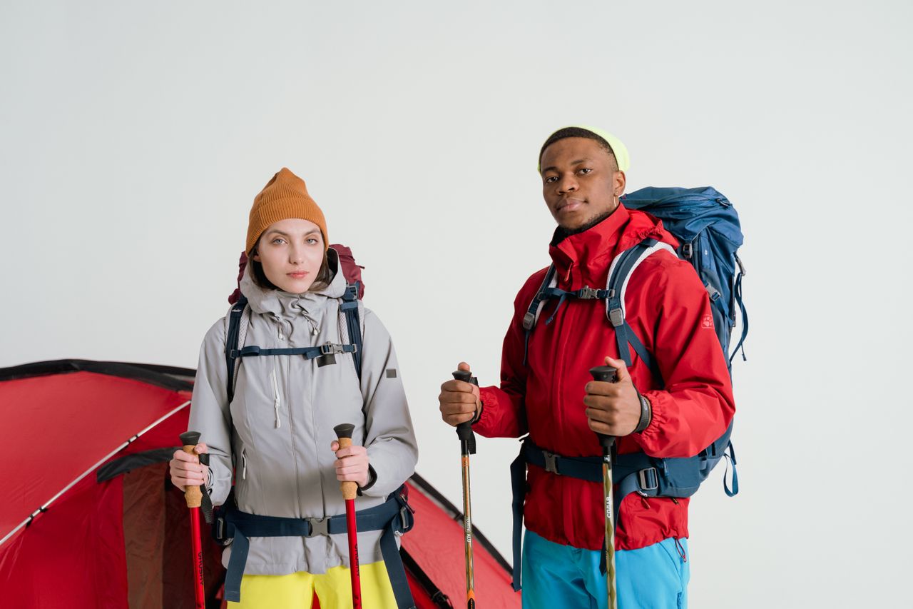 Couple ready for trekking with camping gear, showcasing modern adventure lifestyle.