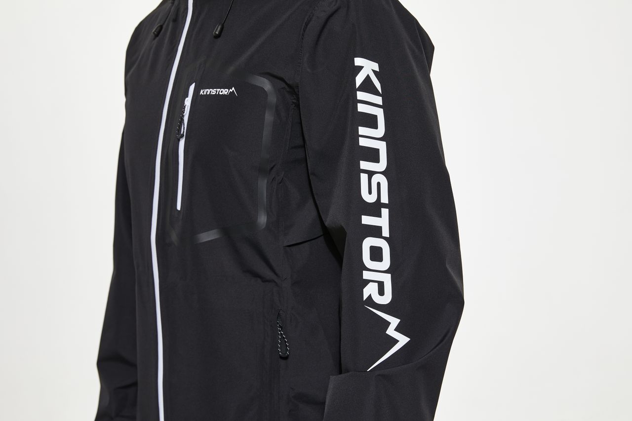 Close-up shot of a black jacket featuring KINNSTORM branding on the sleeve for fashion and lifestyle use.